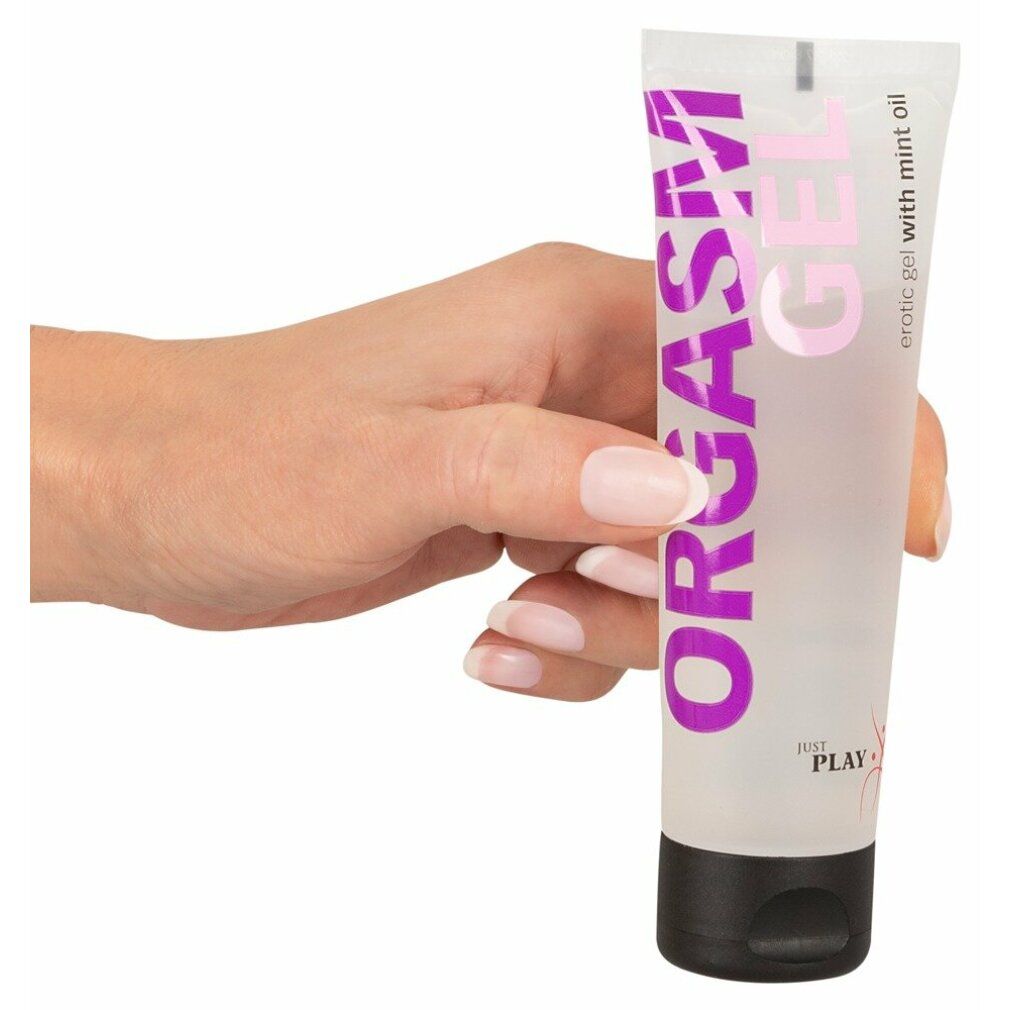 Hand hält Tube "ORGASM GEL". Transparentes Gel mit schwarzem Verschluss. "Just Play" Logo.
