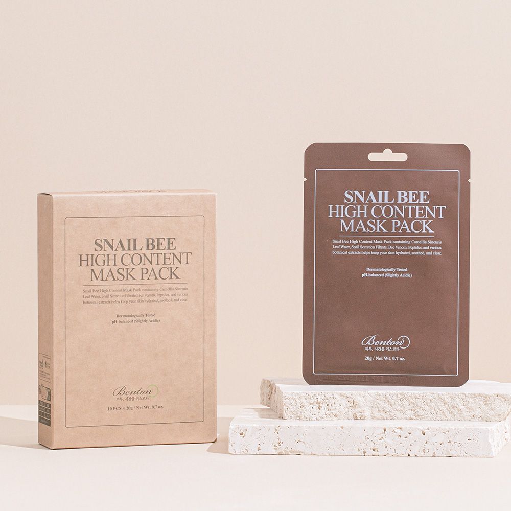 Karton und Einzelverpackung. Aufschrift: Snail Bee High Content Mask Pack. Braune Verpackung, weißer Text. Auf Podest platziert.