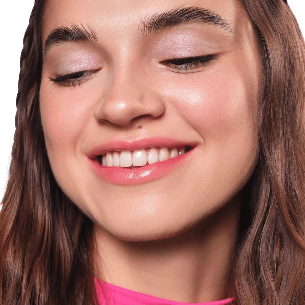 Porträt einer Frau mit geschlossenen Augen. Auf den Augenlidern ist Glitzer-Lidschatten aufgetragen. Rosa Oberteil.