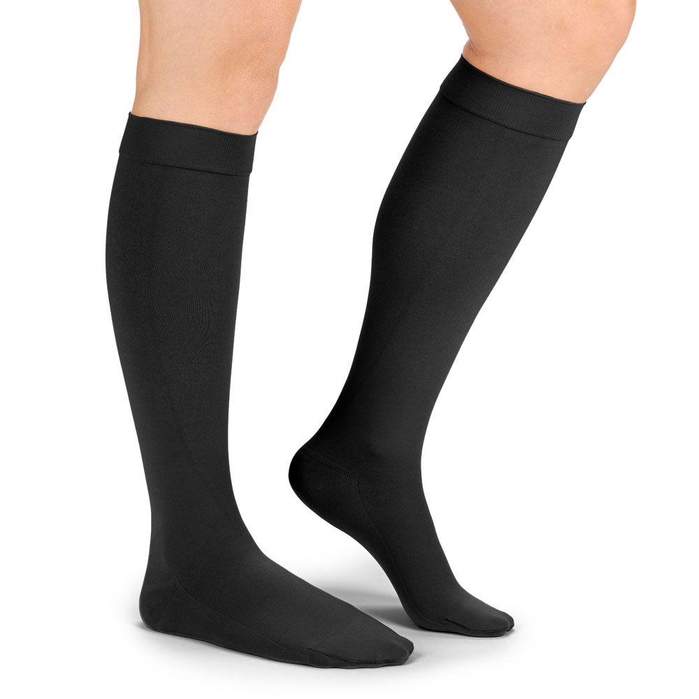 Schwarze Kompressionsstrümpfe, knielang, an einer Person getragen. Glattes Material, ohne Muster.