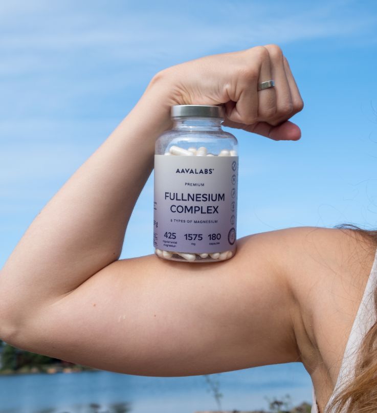 Frau präsentiert Aavalabs Magnesium Komplex Flasche auf dem Bizeps.