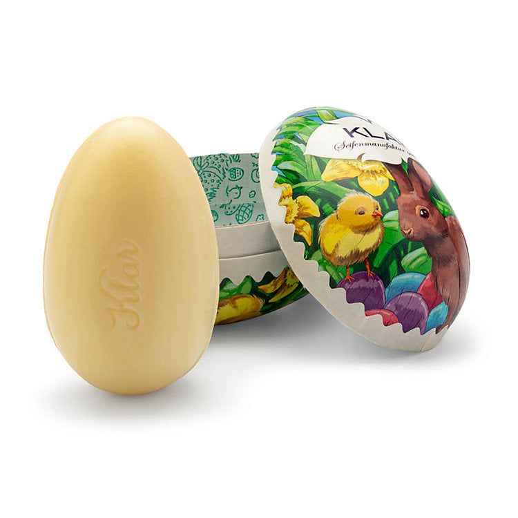 Eiförmige Seife neben geöffneter Eierverpackung mit Hase und Küken. Seife mit Schriftzug: Klar.