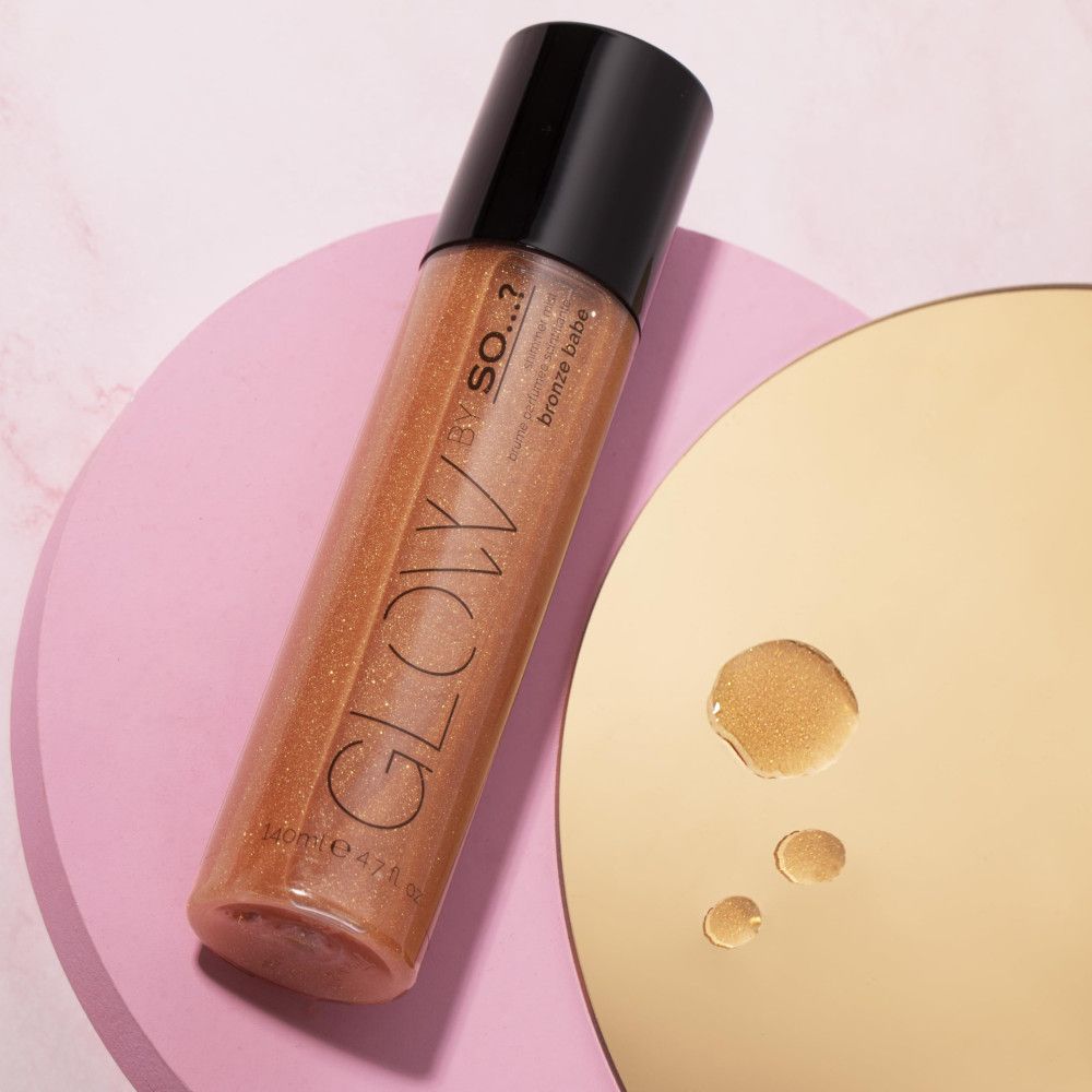 Körper-Duftspray. Bronze-Farbton. Schwarzer Sprühkopf. Auf rosa und goldenen Oberflächen. Produktname: GLOW BY SO...?