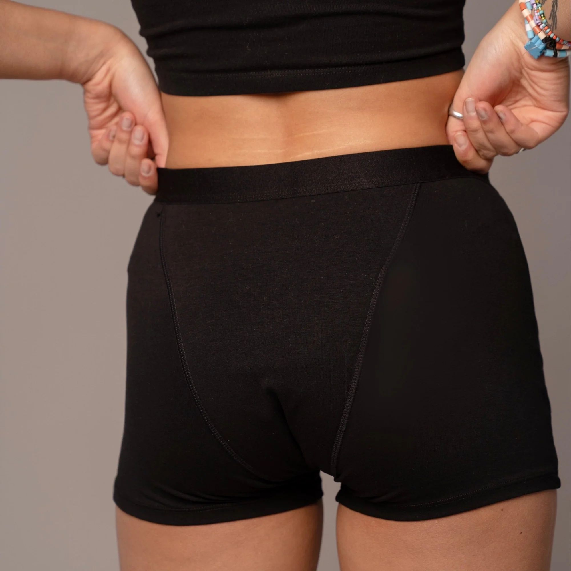 Rückansicht der schwarzen Periodenunterwäsche in Boxer-Form. Nahtdetails.