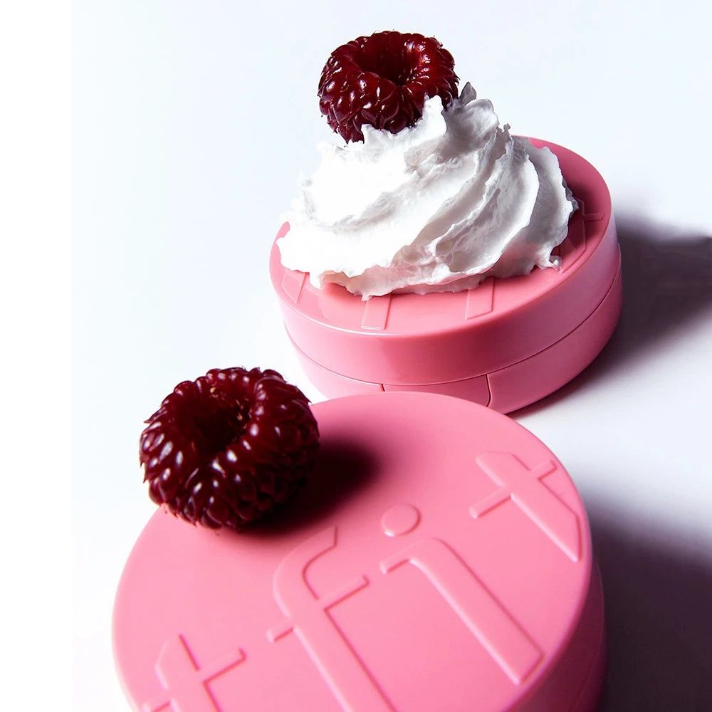Zwei runde, rosafarbene Behälter mit Himbeeren und Sahne-Dekoration.