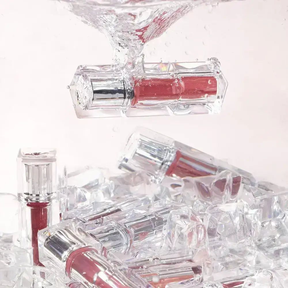 Klarer Lippenstiftbehälter mit silberner Kappe und rotem Inhalt, teilweise in Wasser und Eis.