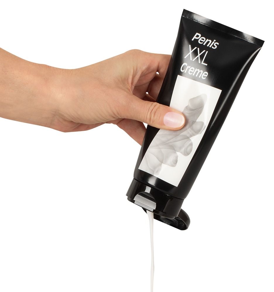 Hand drückt Creme aus schwarzer Tube. Aufschrift: Penis XXL Creme. Weißes Etikett mit Penis-Abbildung.