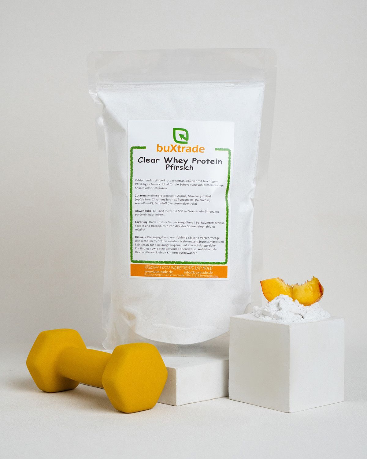 Büchse mit buXtrade Clear Whey Protein Pfirsich, daneben eine gelbe Hantel und ein Würfel mit Pfirsichstücken.