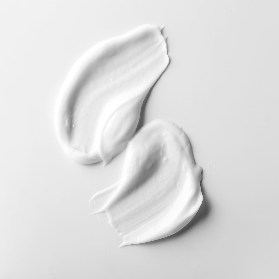 Zwei cremefarbene Cremestriche auf weißem Hintergrund. Glatte Textur.