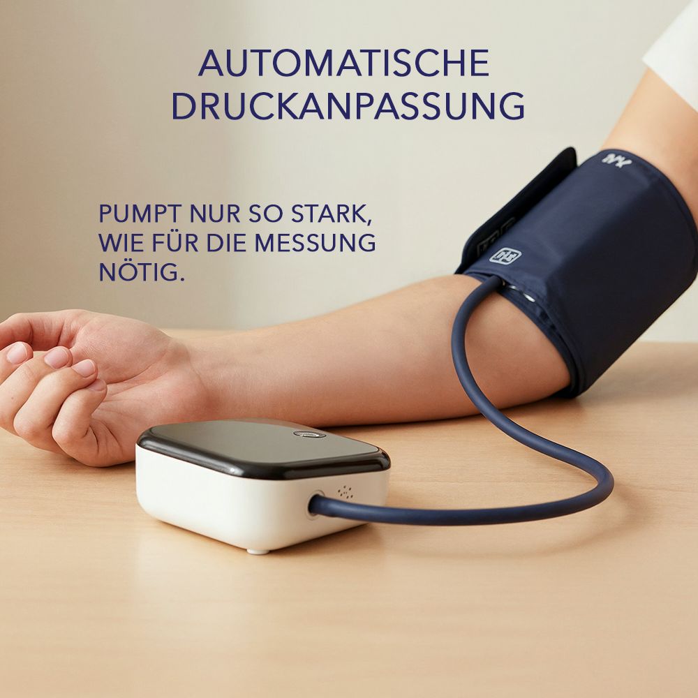 Arm mit Manschette, verbunden mit einem Blutdruckmessgerät. Das Gerät ist weiß mit schwarzem Display.