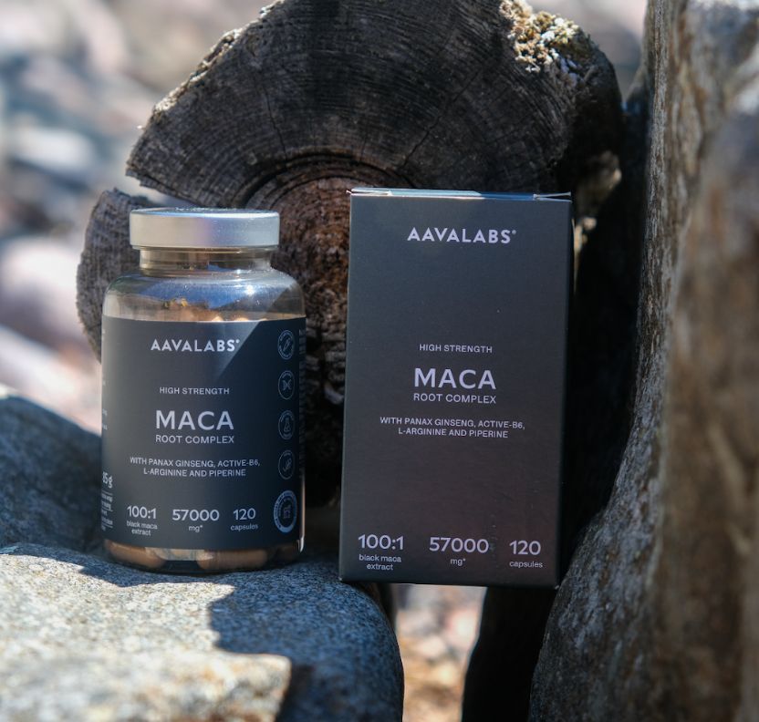 Flasche und Karton mit Maca-Kapseln neben Steinen und Holz.