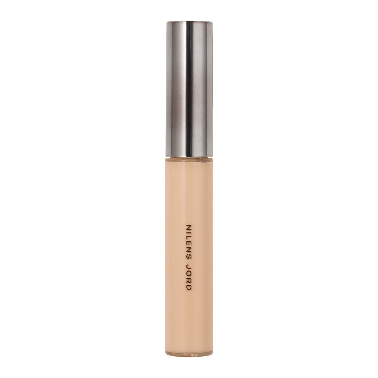 Beige Concealer-Tube mit silberfarbenem Deckel. Aufschrift: NILENS JORD. Vertikale Ansicht.