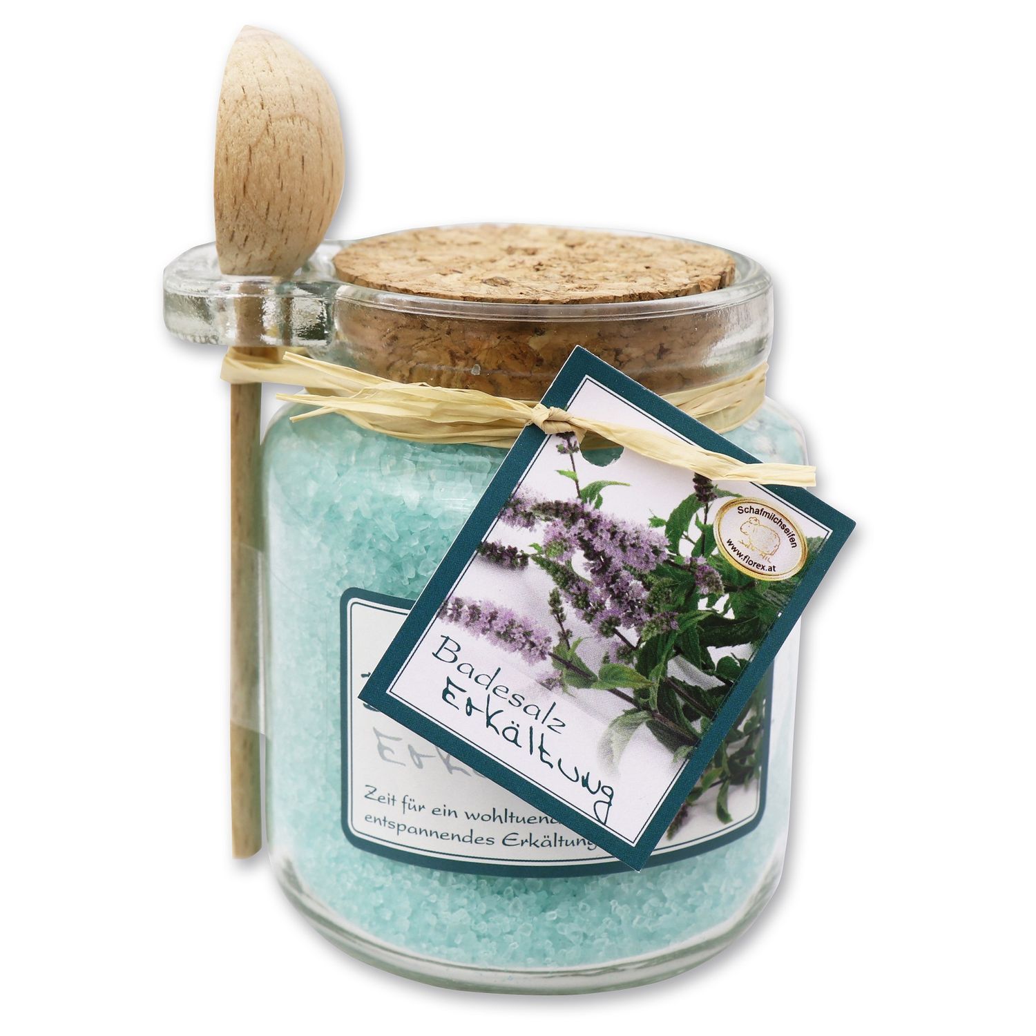 Glas mit türkisfarbenem Badesalz, Holzlöffel, Korken, Etikett mit Text und Kräutern.