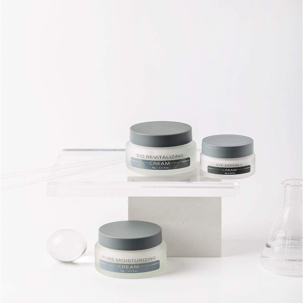 Drei Creme-Gläser mit Deckel. Aufschrift: Pure Moisturizing Cream, Bio Revitalizing Cream, Eye Solution Cream.
