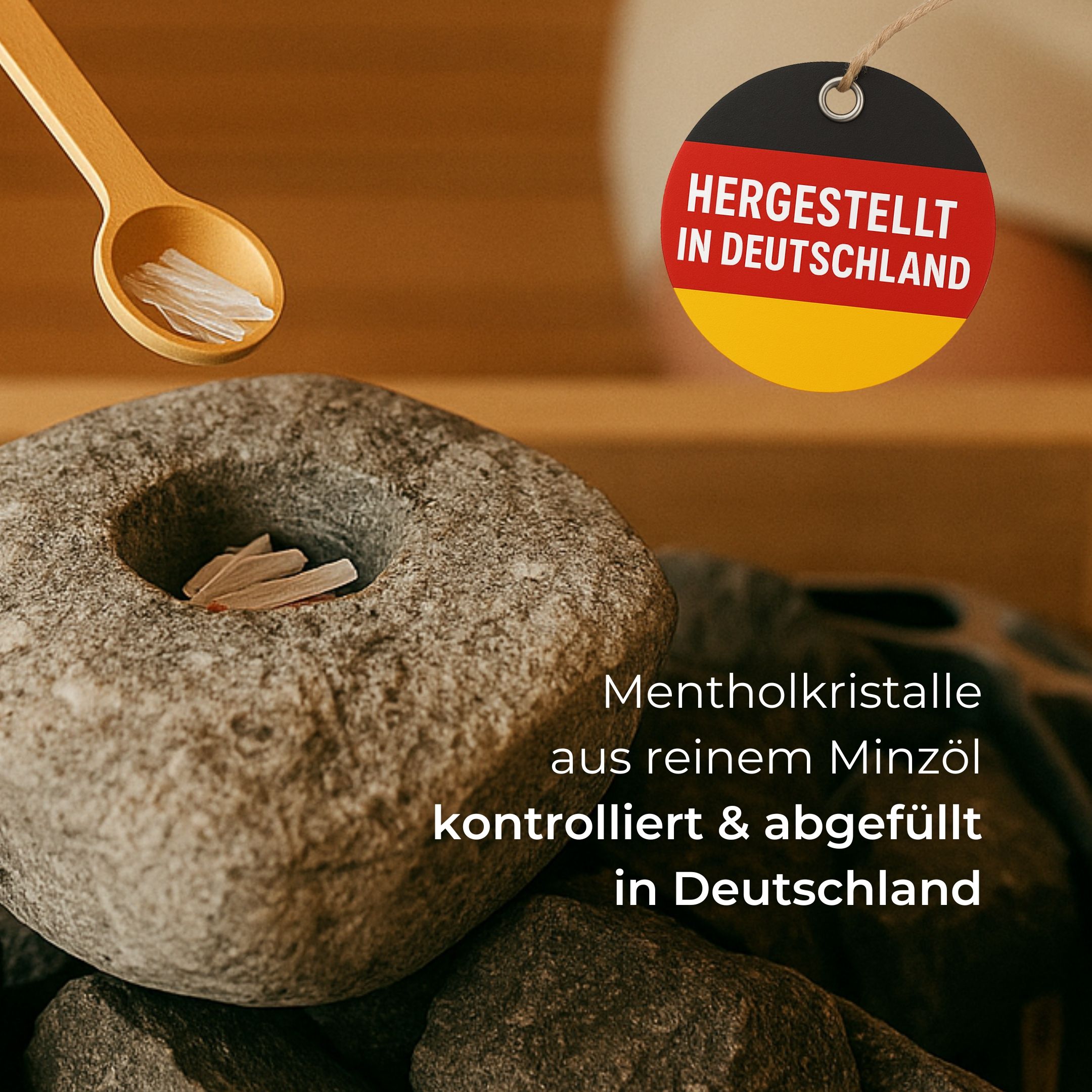 Holzlöffel mit Mentholkristallen auf Saunasteinen. Aufschrift: Hergestellt in Deutschland. Text: Mentholkristalle aus reinem Minzöl.