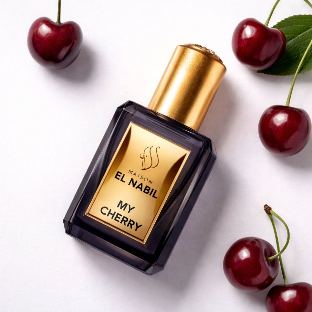 Dunkle Parfumflasche mit goldfarbenem Verschluss und Etikett. Kirschen umgeben die Flasche. Aufschrift: El Nabil, My Cherry.