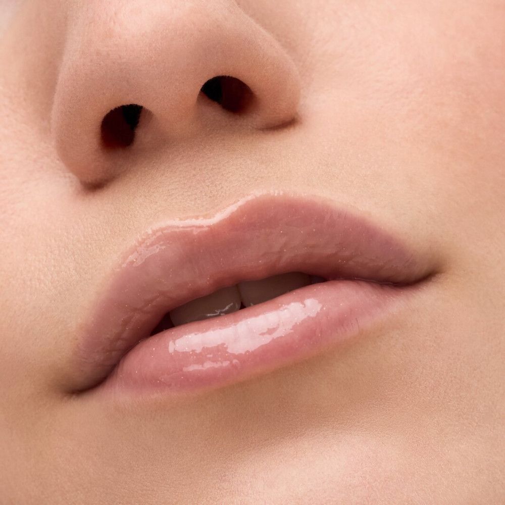 Nahaufnahme von Lippen, die mit Lipgloss bedeckt sind. Die Lippen sind glänzend und haben einen rosafarbenen Farbton.