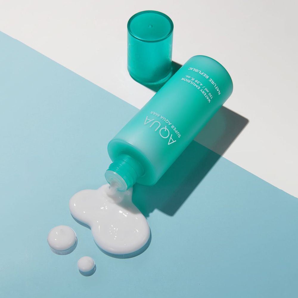Türkisfarbene Flasche, aus der eine weiße Emulsion auf eine blaue Oberfläche fließt. Produkt: AQUA Super Aqua Max Watery Emulsion.
