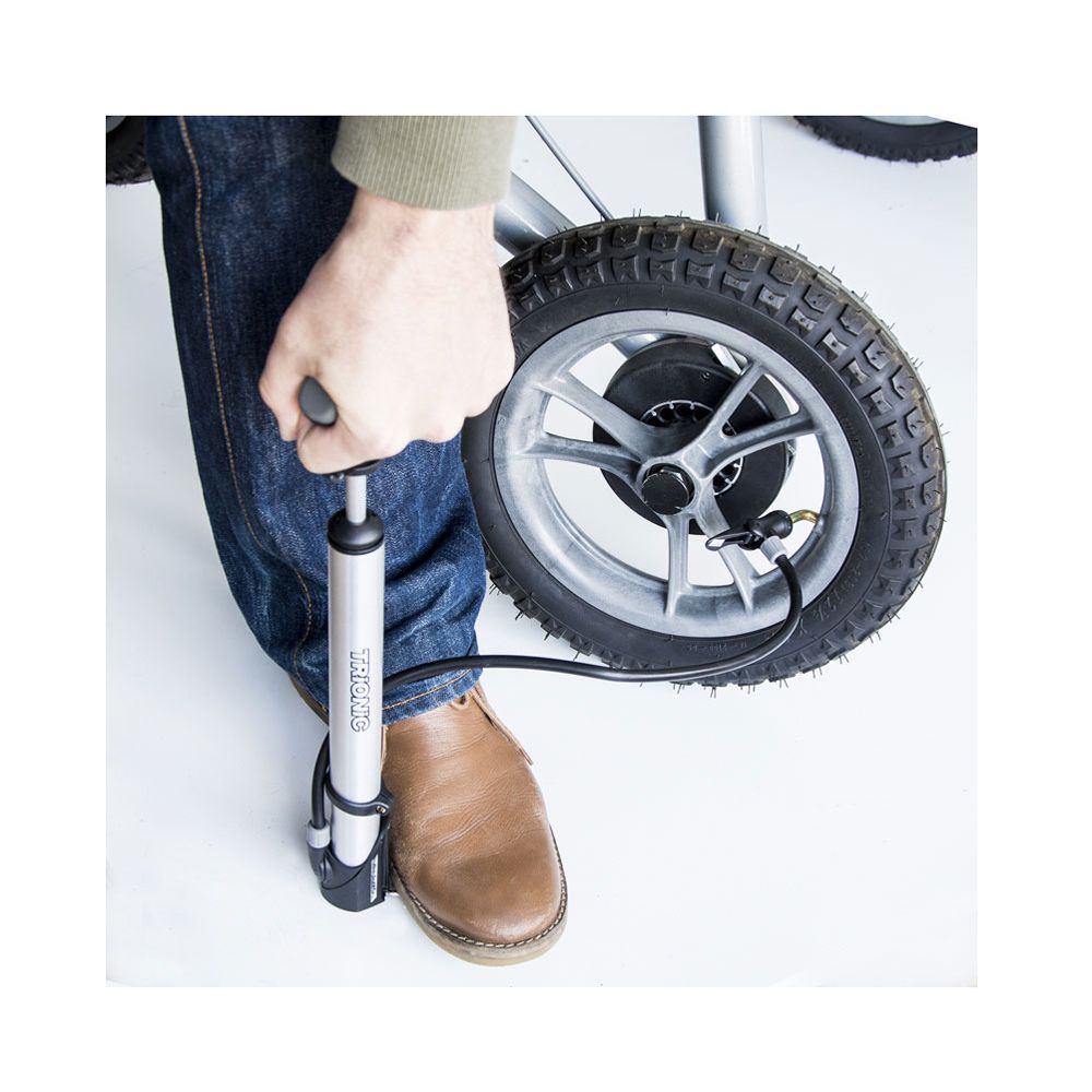 Person pumpt Reifen mit Luftpumpe auf. Silberne Pumpe mit Trionic-Logo. Schwarzer Schlauch.