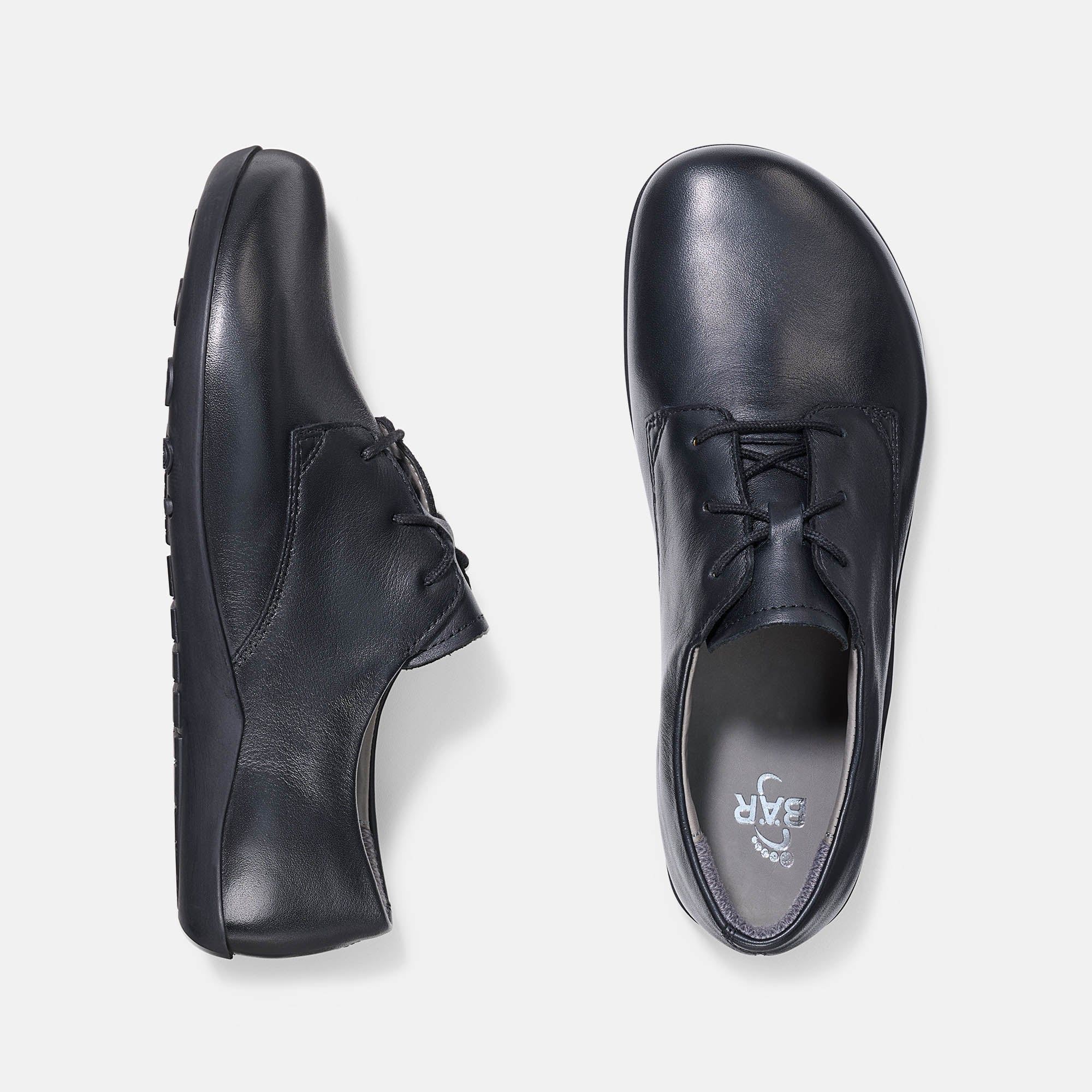 Schwarze Lederschnürschuhe. Breite Passform. Draufsicht auf zwei Schuhe, Sohlen sichtbar.