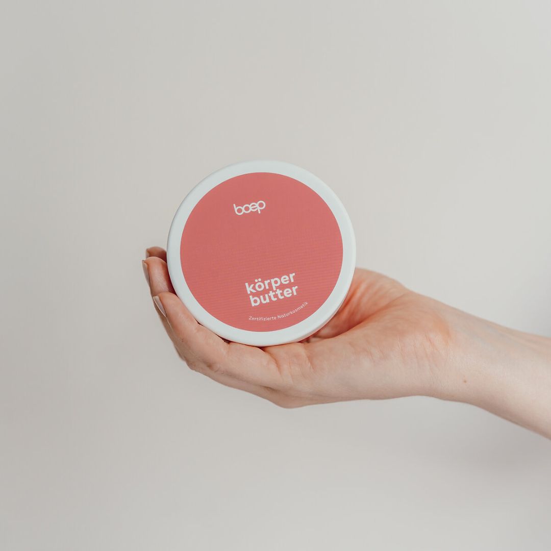 Hand hält runde Dose Körperbutter. Aufschrift: boep, Körperbutter, Zertifizierte Naturkosmetik.