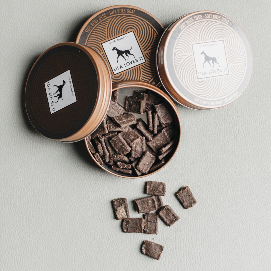 Geöffnete Dose mit Snacks. Zwei weitere Dosen mit Logo LILA LOVES IT. Snacks liegen daneben.