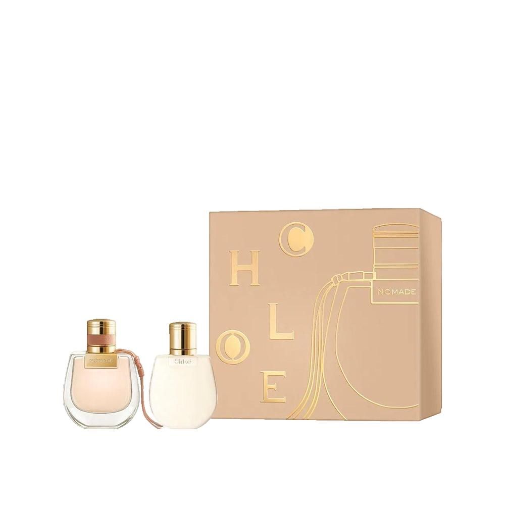 Geschenkset mit zwei Parfümflakons und einer rechteckigen Verpackung. Flakons mit goldenen Verschlüssen und hellen Flüssigkeiten. Verpackung mit Schriftzug.
