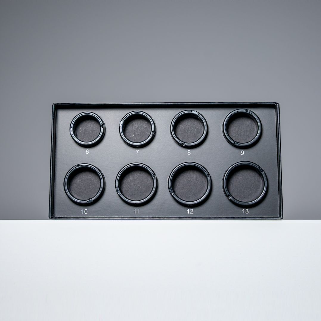 Schwarze Box mit acht kreisförmigen Aussparungen für Ringe. Zahlen 6-13.