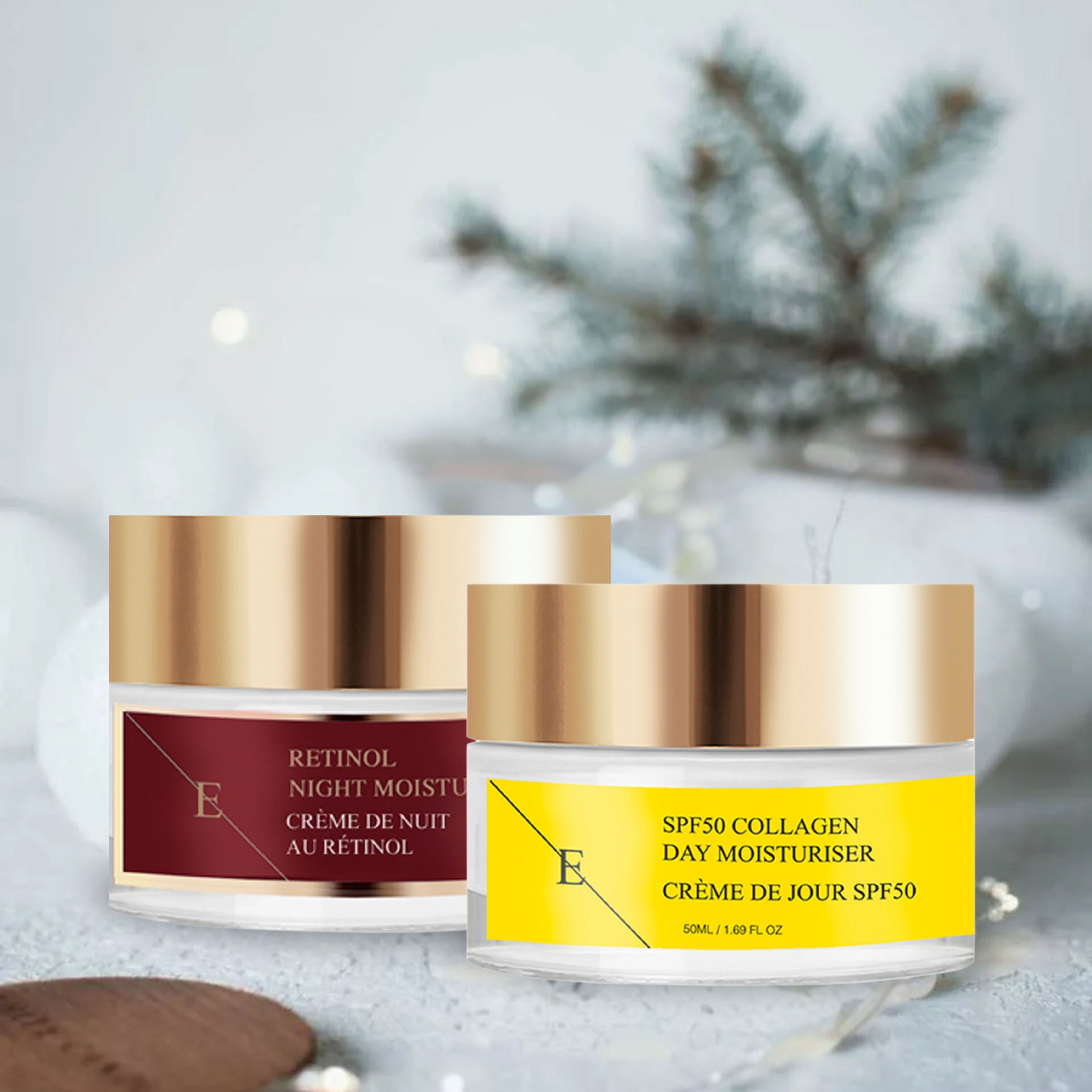 Zwei Cremetiegel mit goldenen Deckeln. Links: Rote Etikette mit Text. Rechts: Gelbe Etikette mit Text. Beide mit "E" Logo. Hintergrund: verschwommene Dekoration.