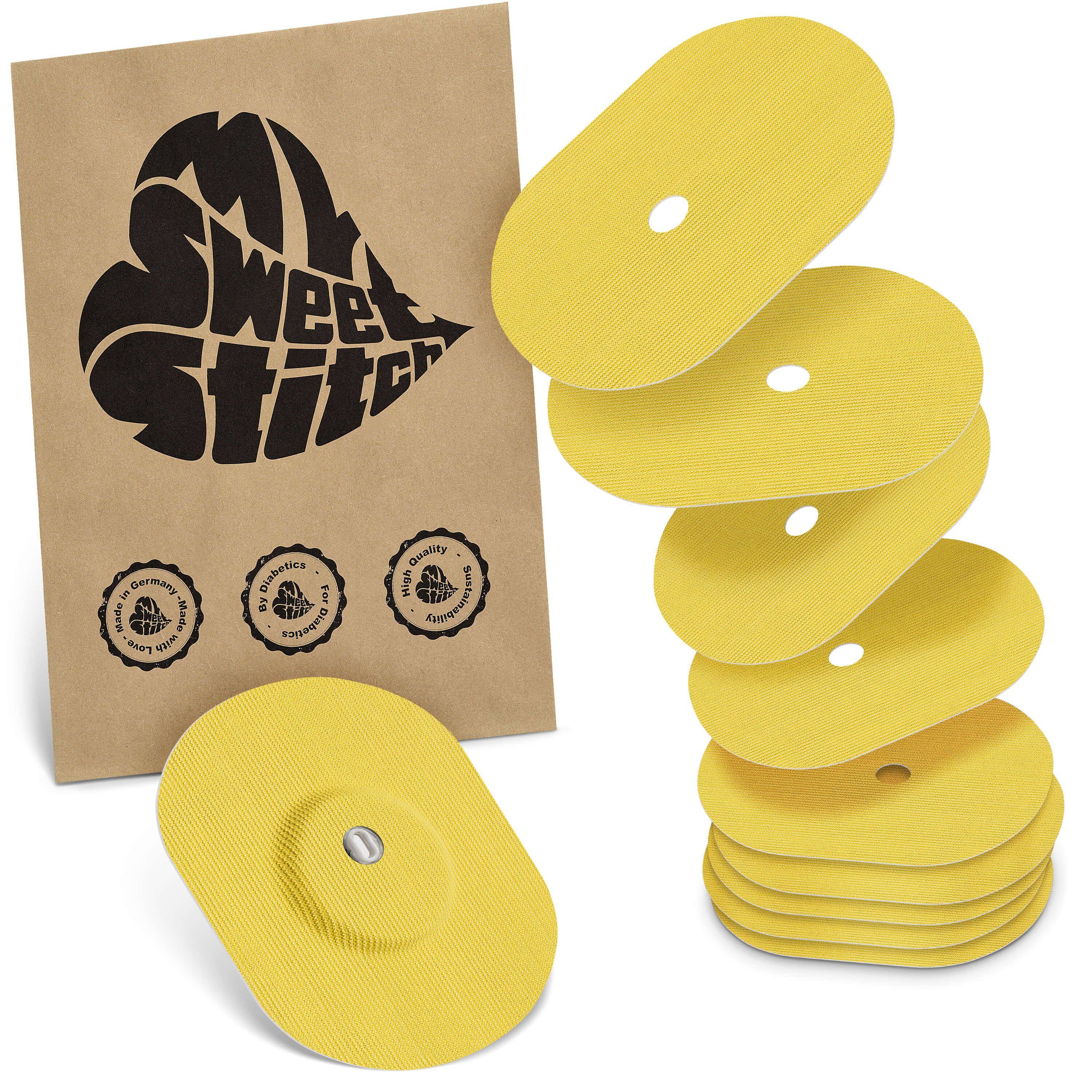 Gelbe, ovale Pflaster mit Loch, neben einer braunen Verpackung mit Logo. Einige Pflaster sind gestapelt.