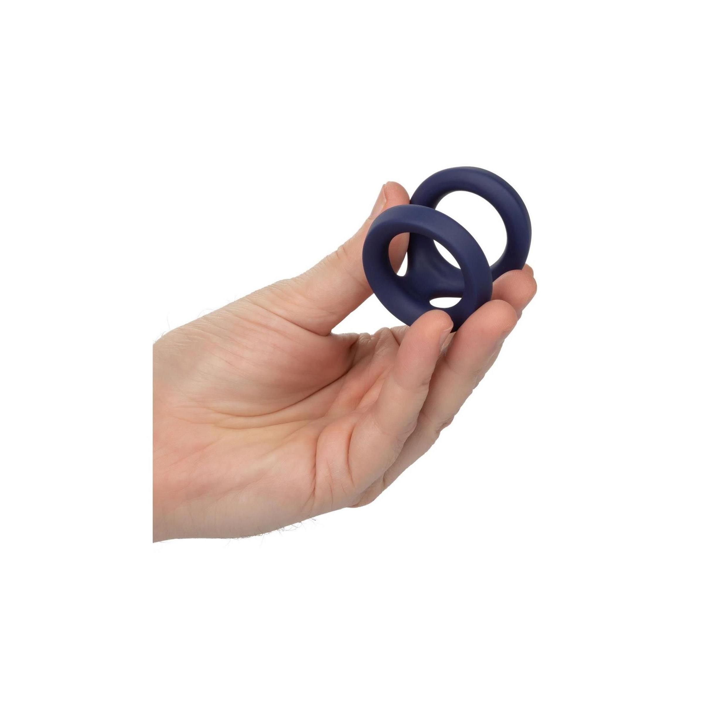 Hand hält einen dunkelblauen CalExotics Viceroy Dual Ring. Der Ring hat zwei Öffnungen.