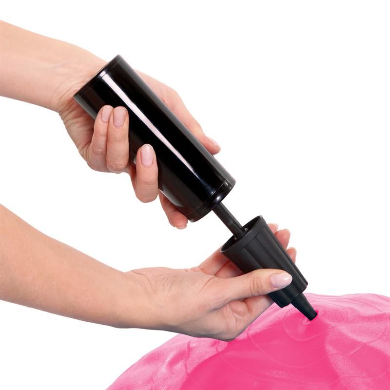 Hände halten eine schwarze Handpumpe. Die Pumpe wird an einen pinkfarbenen Gymnastikball angeschlossen.