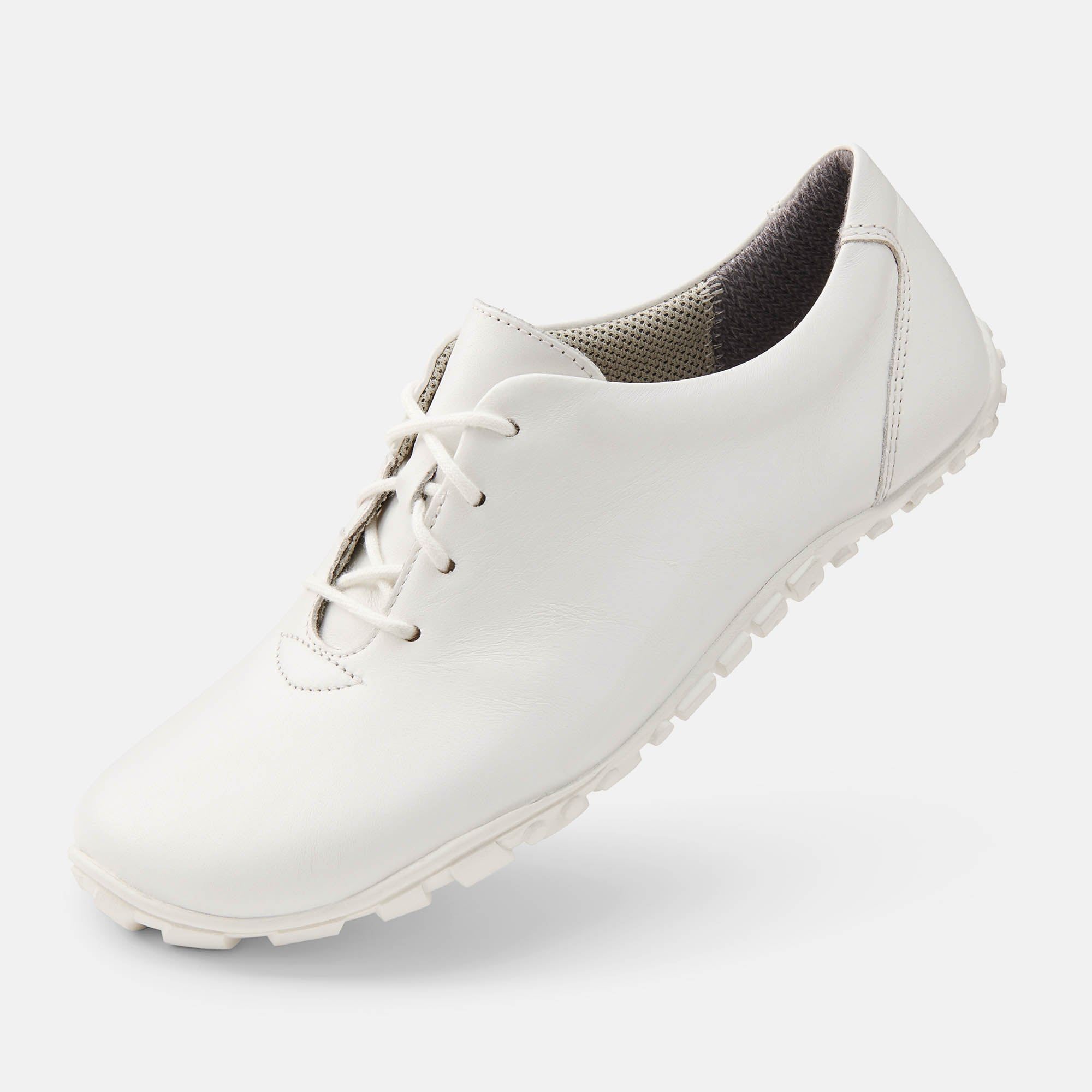Weißer Schnürschuh. Flache Sohle, Schnürsenkel. Innenfutter grau. Schuh leicht schräg.