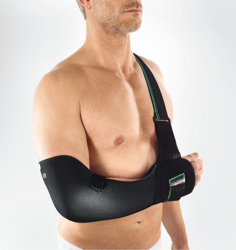 Mann mit schwarzer Cellacare Gilchrist Sling Schulterorthese. Schwarzes Material, grüner Akzent, Träger.