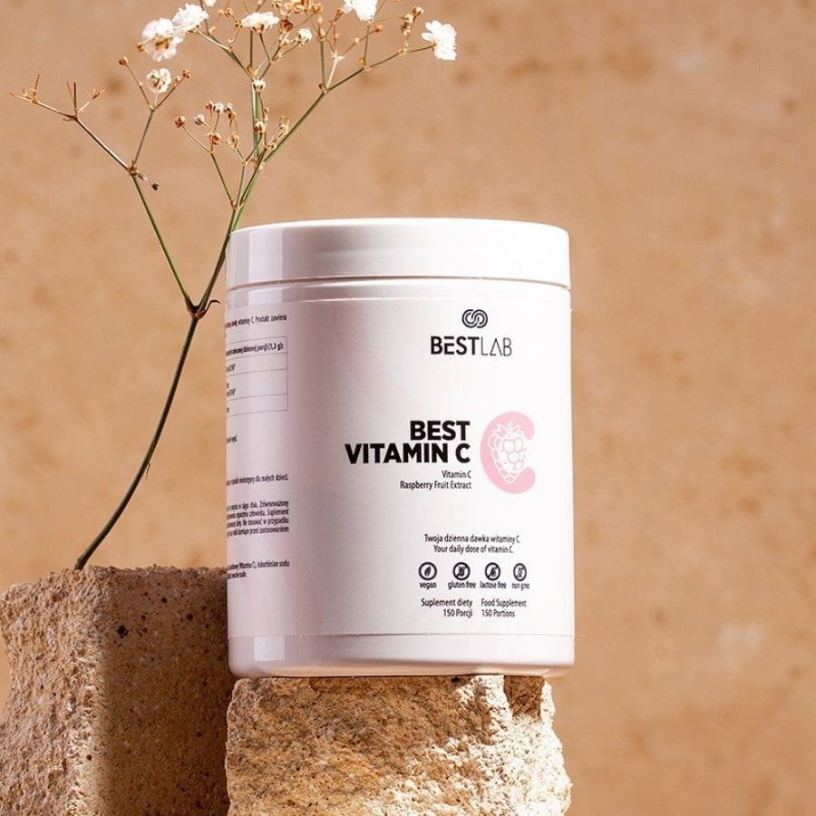 Weißer Behälter mit BEST VITAMIN C. Himbeer-Fruchtextrakt. Vegan, glutenfrei, ohne Zucker, ohne Gentechnik. Auf Steinblock platziert.
