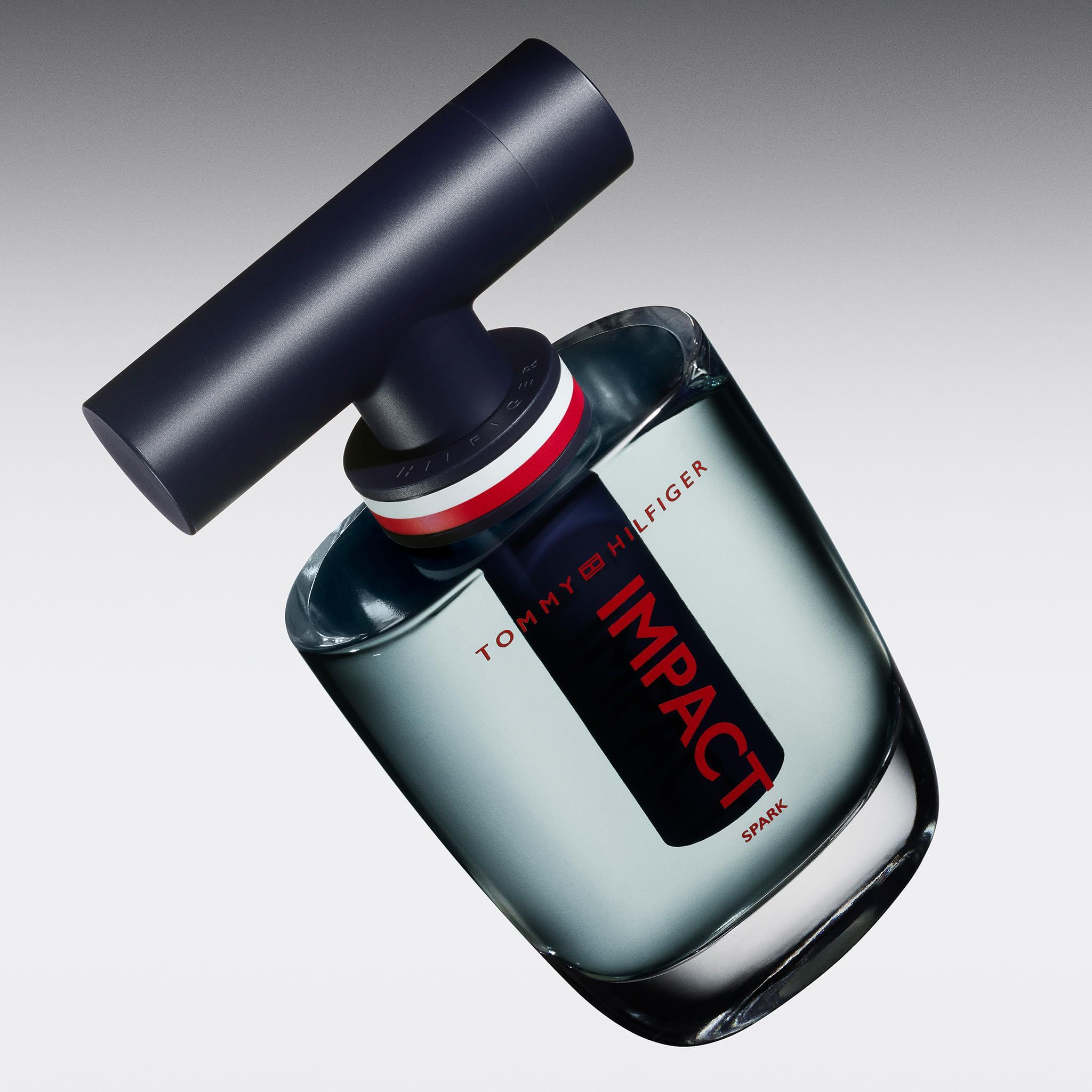 Tommy Hilfiger Impact Spark Eau de Toilette. Schräg gestellter Flakon. Blau, rot und weiß.