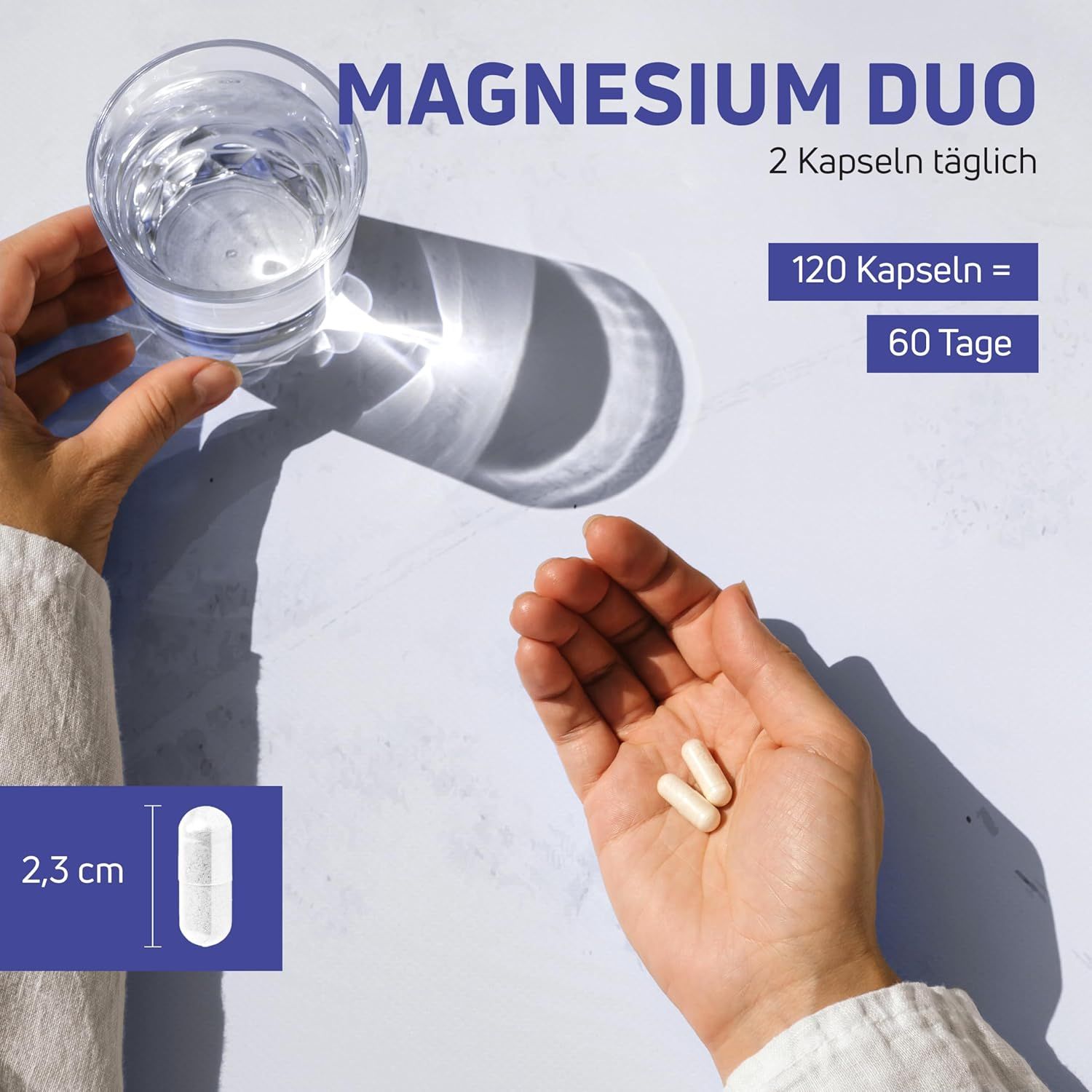 Hände halten zwei Kapseln. Daneben ein Glas Wasser. Auf der linken Seite ist die Größe der Kapsel angegeben: 2,3 cm.