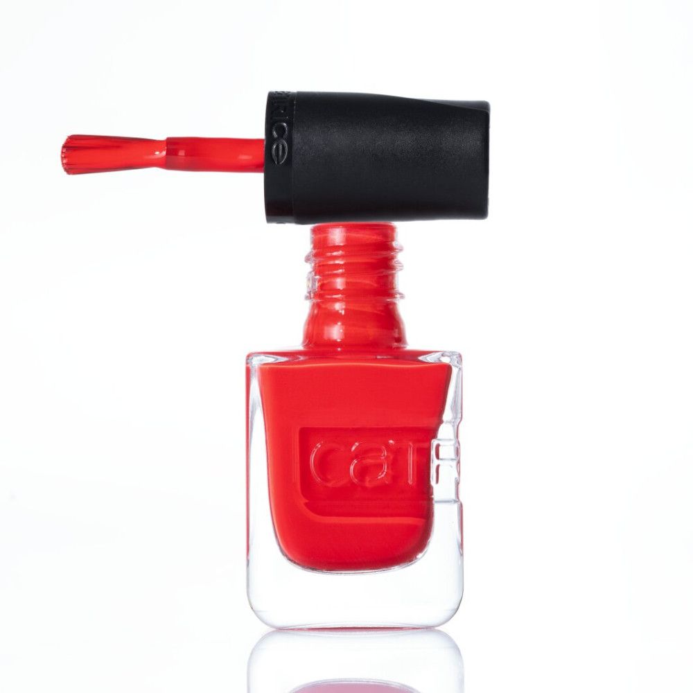 Roter Nagellack in einem durchsichtigen Flakon mit schwarzem Deckel und Pinsel.