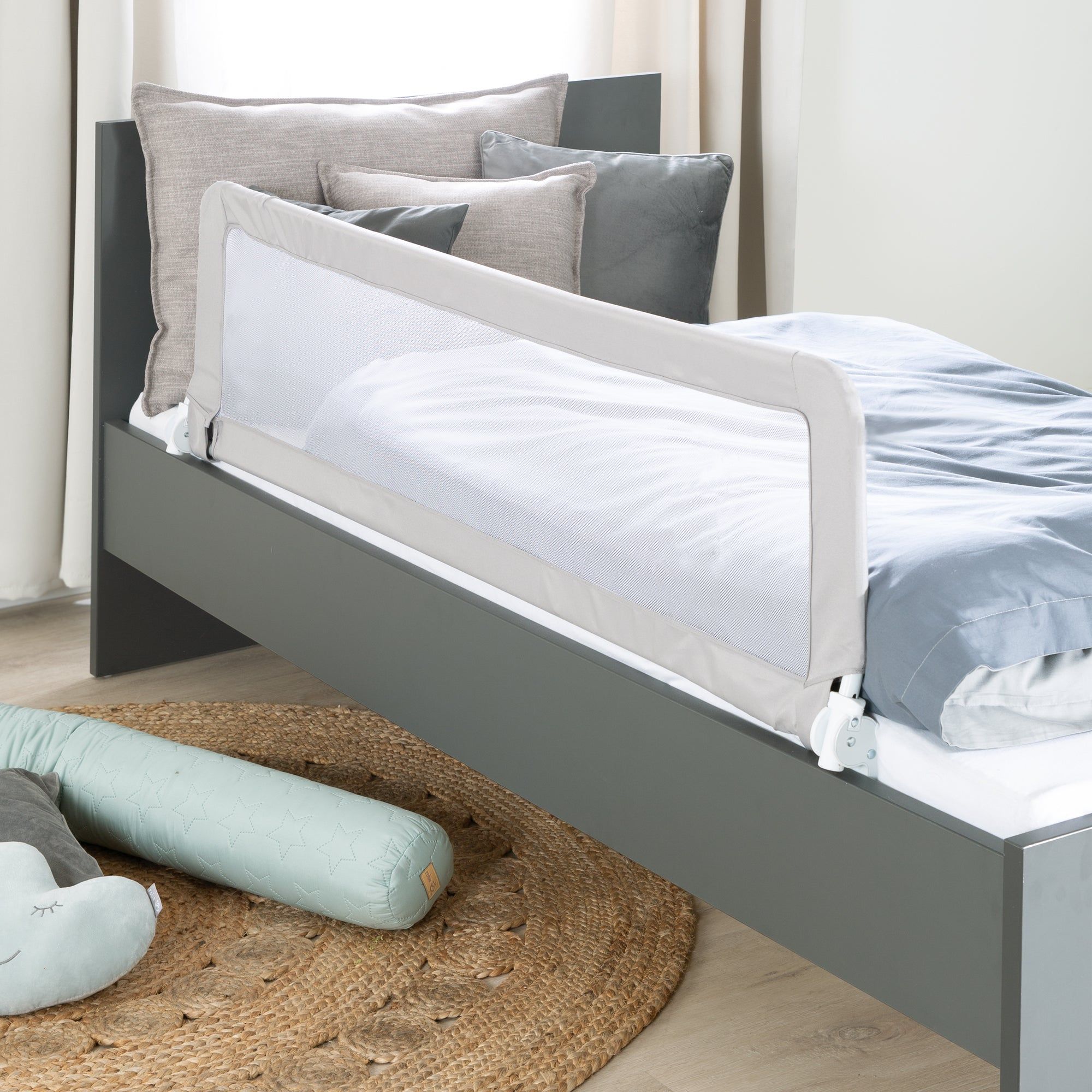 Bettgitter, weißes Netz, grauer Rahmen, an einem grauen Bett befestigt. Auf einer runden Matte.