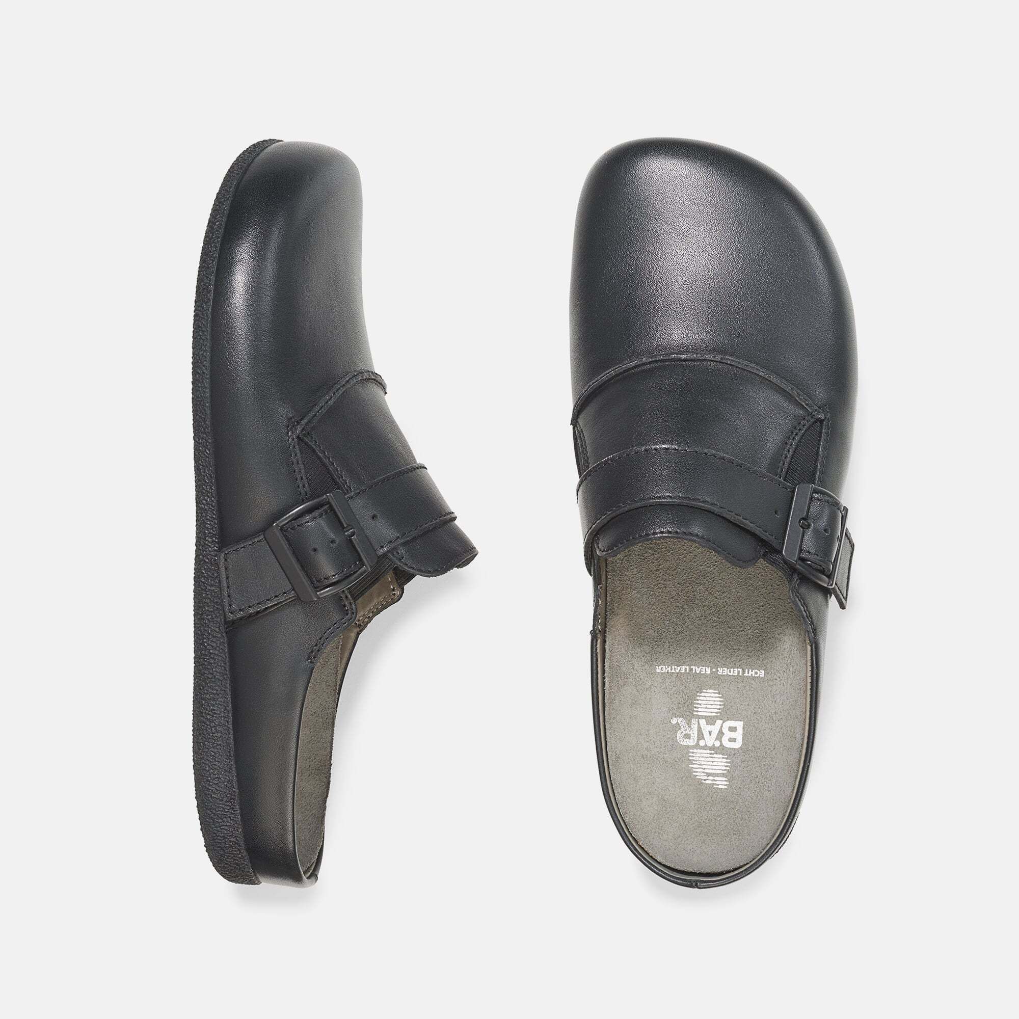 Draufsicht auf zwei schwarze Pantoletten. Eine zeigt die Sohle, die andere die Oberseite mit Riemen und Schnalle. Innen BÄR-Logo.