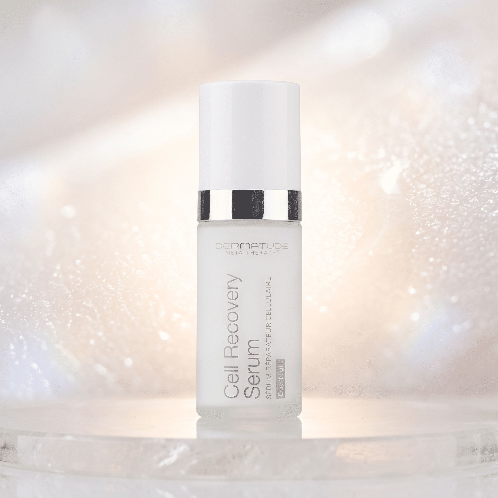 Dermatude Cell Recovery Serum Flasche auf einem hellen, glitzernden Hintergrund.