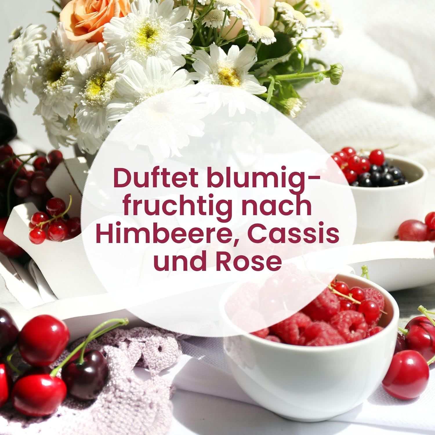 Weiße Schalen mit Himbeeren, Johannisbeeren und Kirschen. Blumenstrauß im Hintergrund. Text: Duftet blumig-fruchtig nach Himbeere, Cassis und Rose.