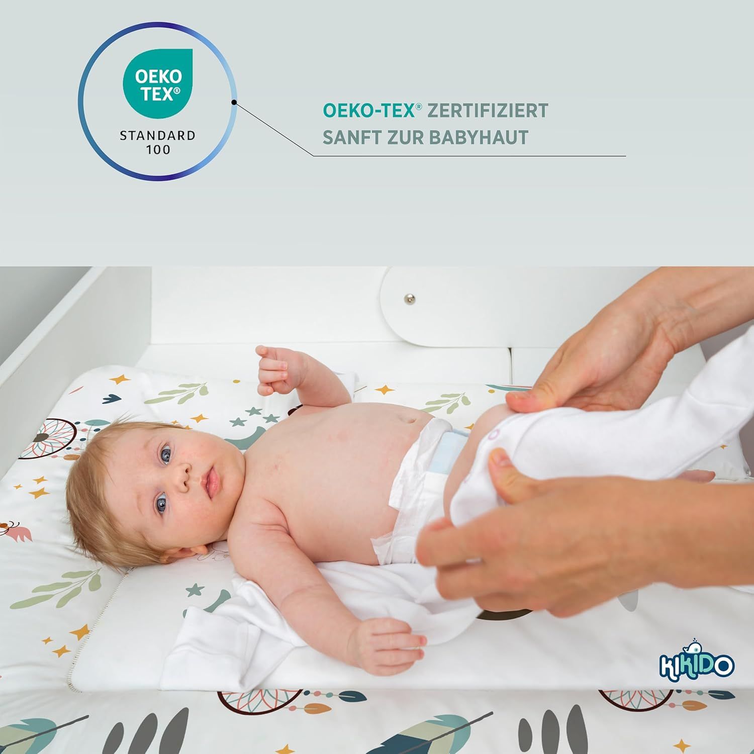 Baby liegt auf Wickelauflage. Text: OEKO-TEX® zertifiziert, sanft zur Babyhaut. OEKO-TEX® Standard 100.
