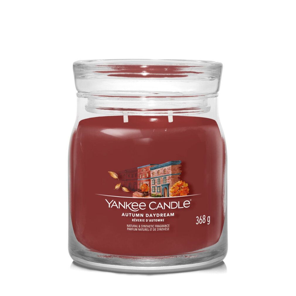 Kerze in Glasbehälter. Aufschrift: Yankee Candle, Autumn Daydream, 368 g. Abbildung von Häusern und Blättern.