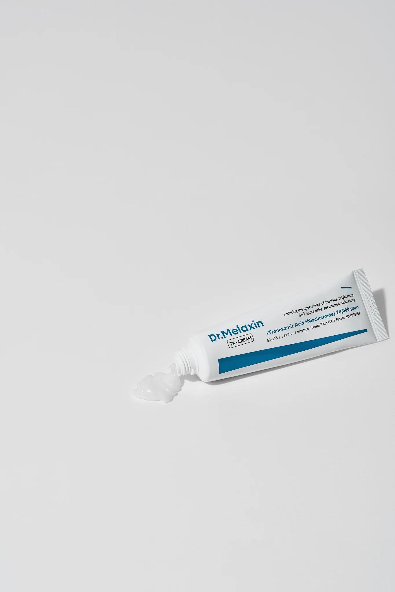 Weiße Tube, Creme tritt aus. Aufschrift: Dr.Melaxin TX-CREAM. Enthält Tranexamsäure und Niacinamid.