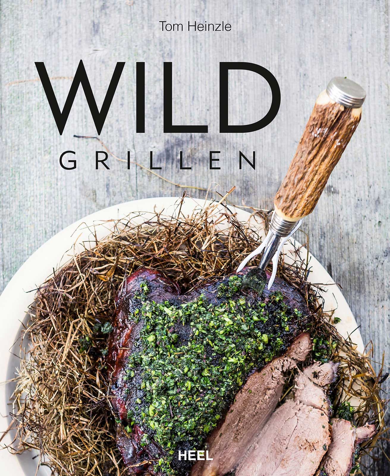 Buchcover mit Titel WILD GRILLEN und Autor Tom Heinzle. Auf einem Teller Fleisch mit Kräutern und Gabel.
