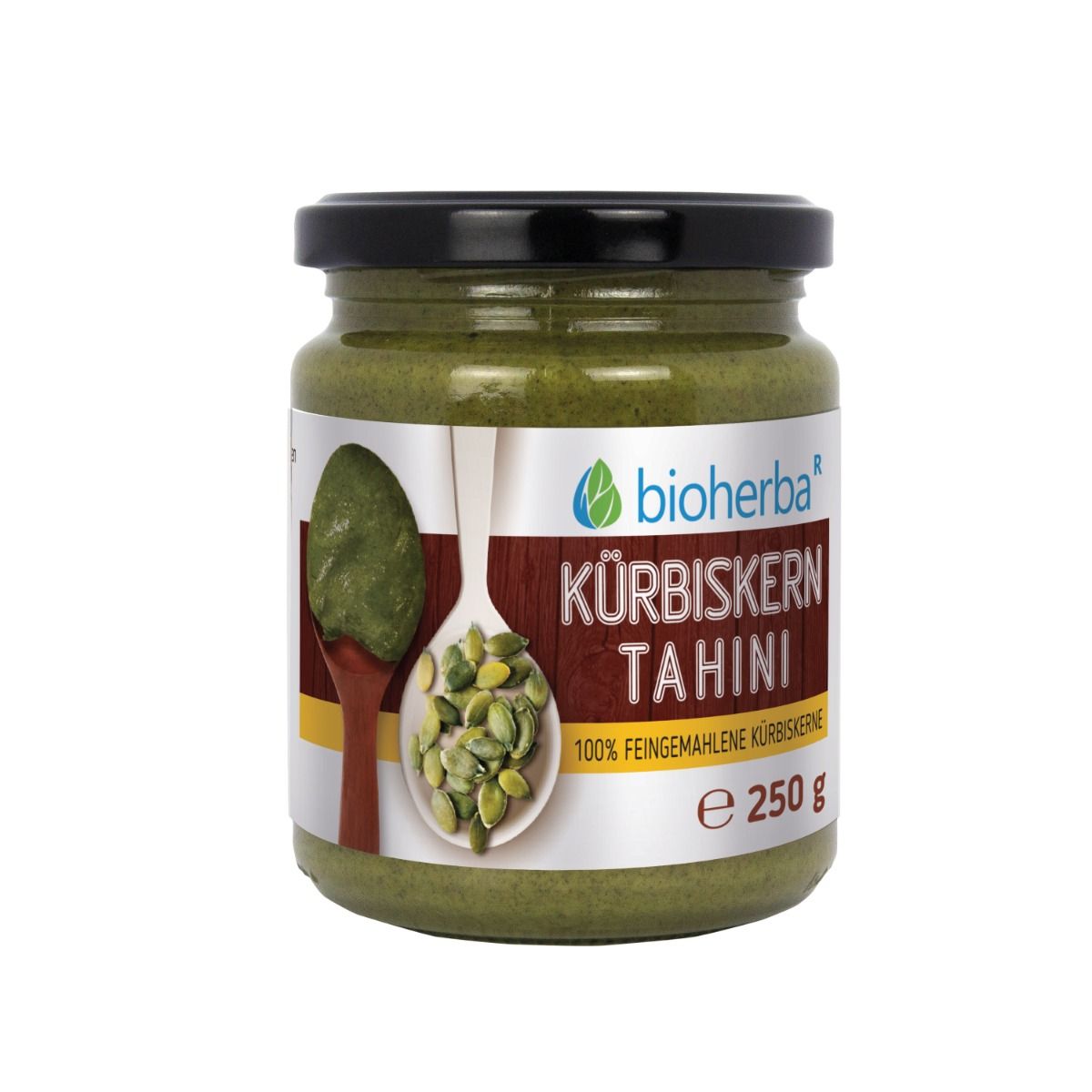 Glas mit Kürbiskern Tahini. Schwarzer Deckel. Etikett mit Produktname und 250 g. Tahini auf Löffel abgebildet.