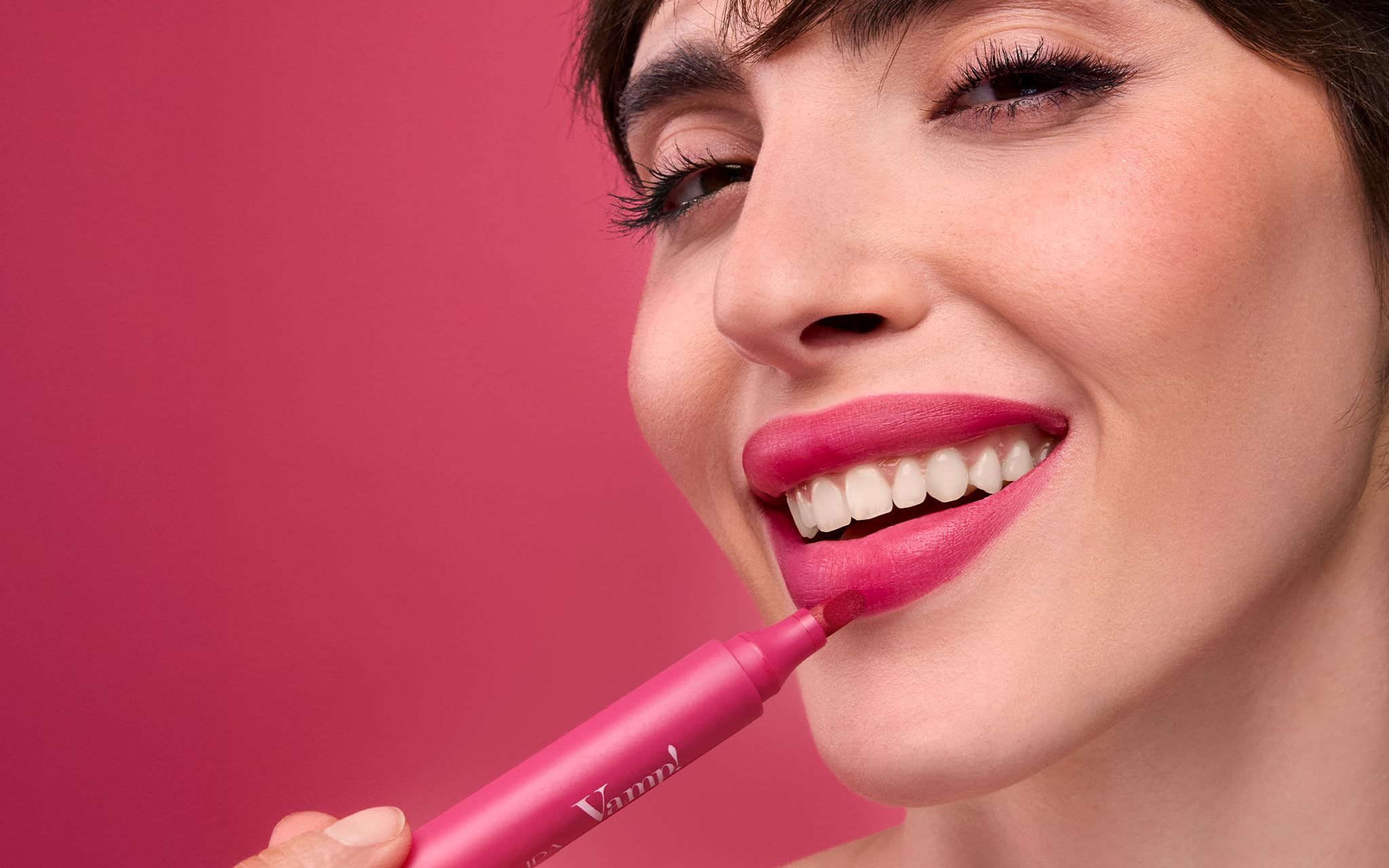 Eine Frau trägt mit einem rosafarbenen Applikator Lippenstift auf.