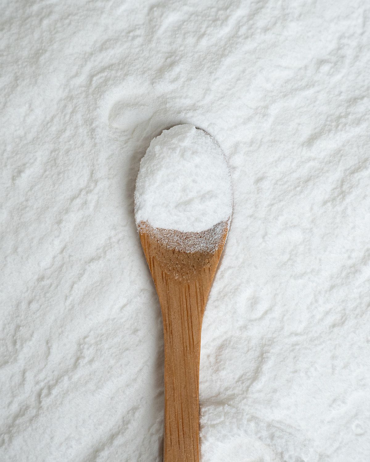 Ein Holzlöffel mit weißem Pulver, Nahaufnahme.