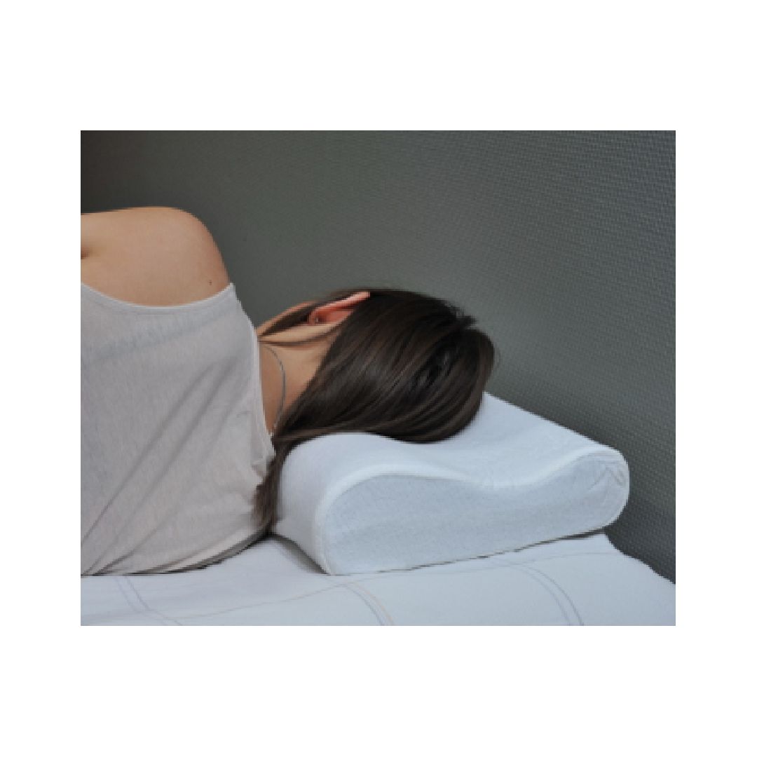 Una persona è sdraiata su un letto bianco, che utilizza un cuscino cervicale ergonomico bianco. Il cuscino ha una forma ondulata e sostiene il collo.